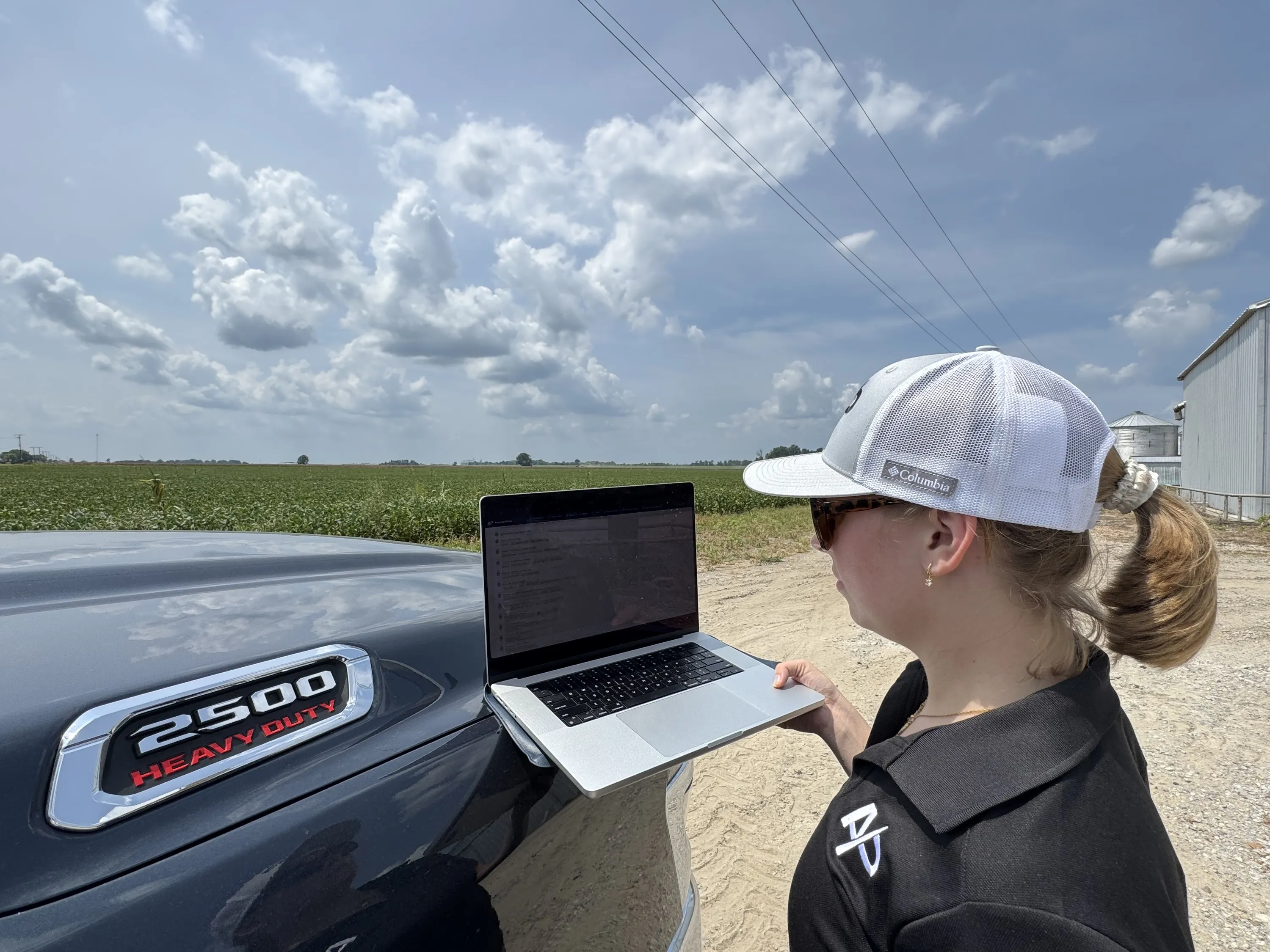 American Prime team member reviewing the AP Intelligence platform on a laptop at the edge of a soybean field